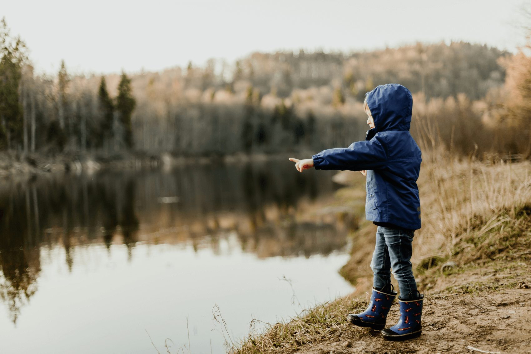 young boy throwing rock into lake