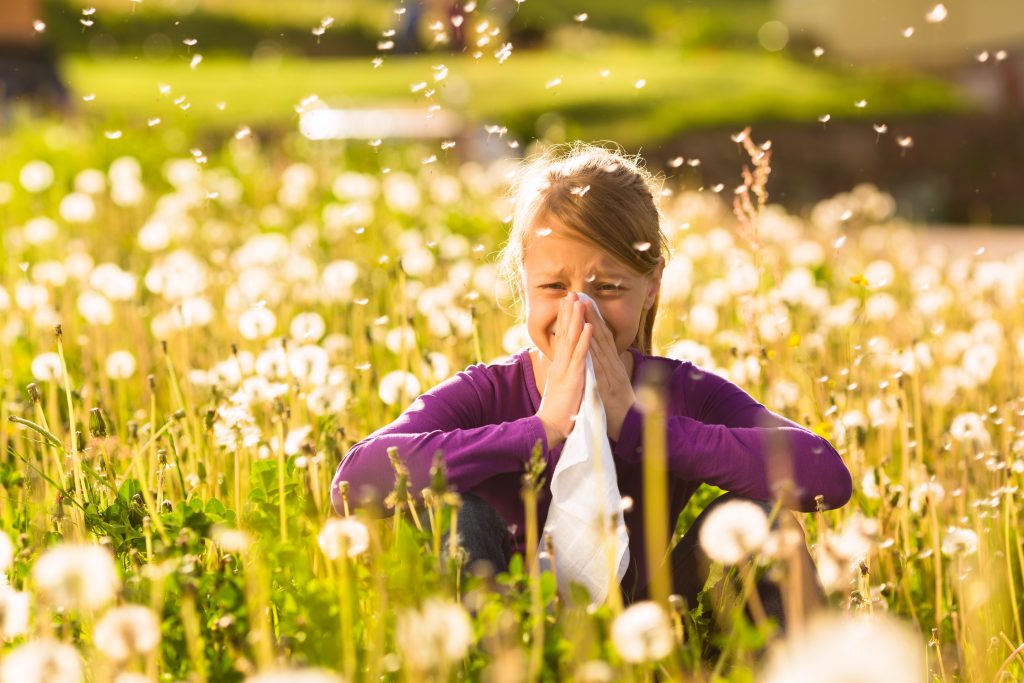 Woman sitting in field blowing nose